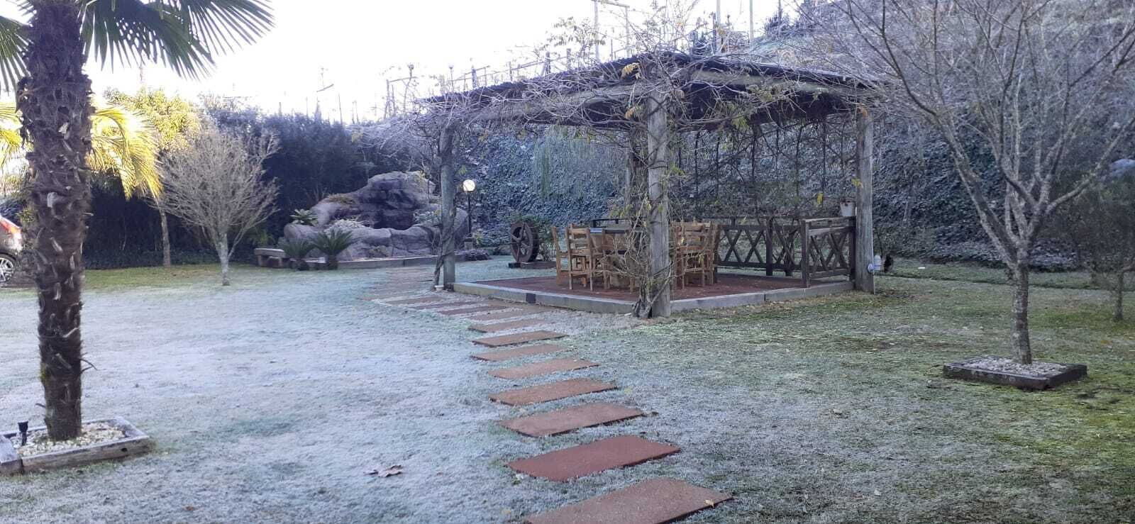 Un jardín con un porche de madera, un camino de piedra y una pequeña mesa con sillas.