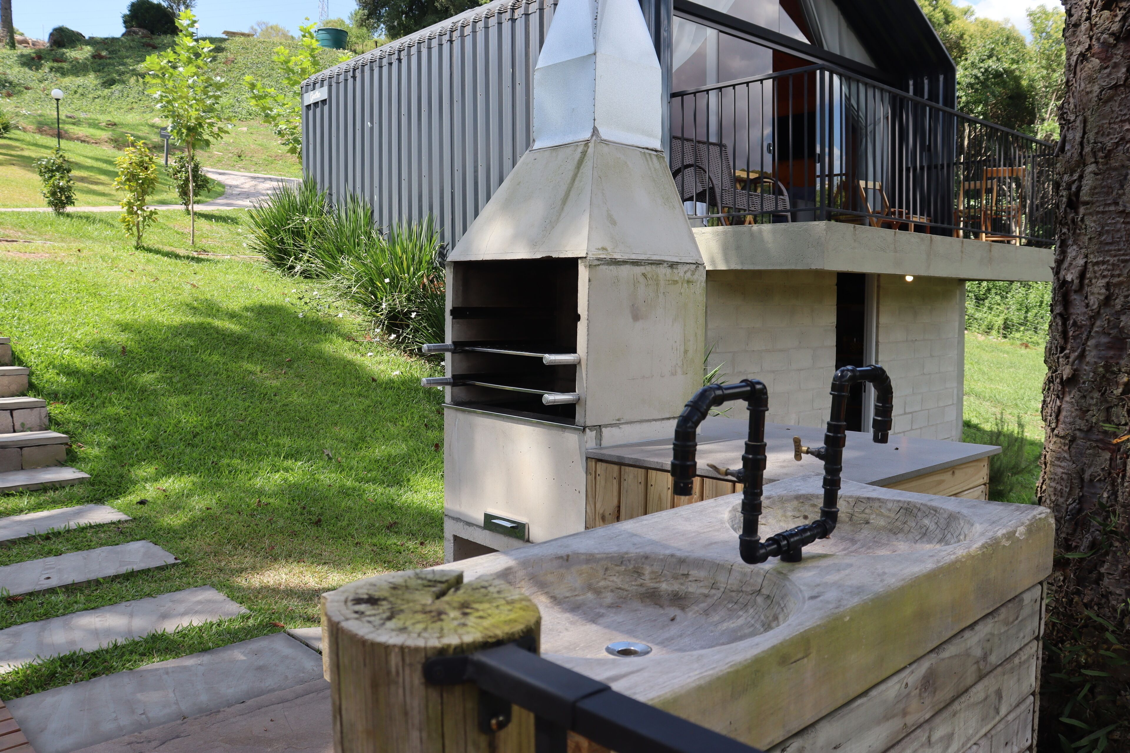 An outdoor kitchen with a chimney, a sink, and a barbecue grill.
