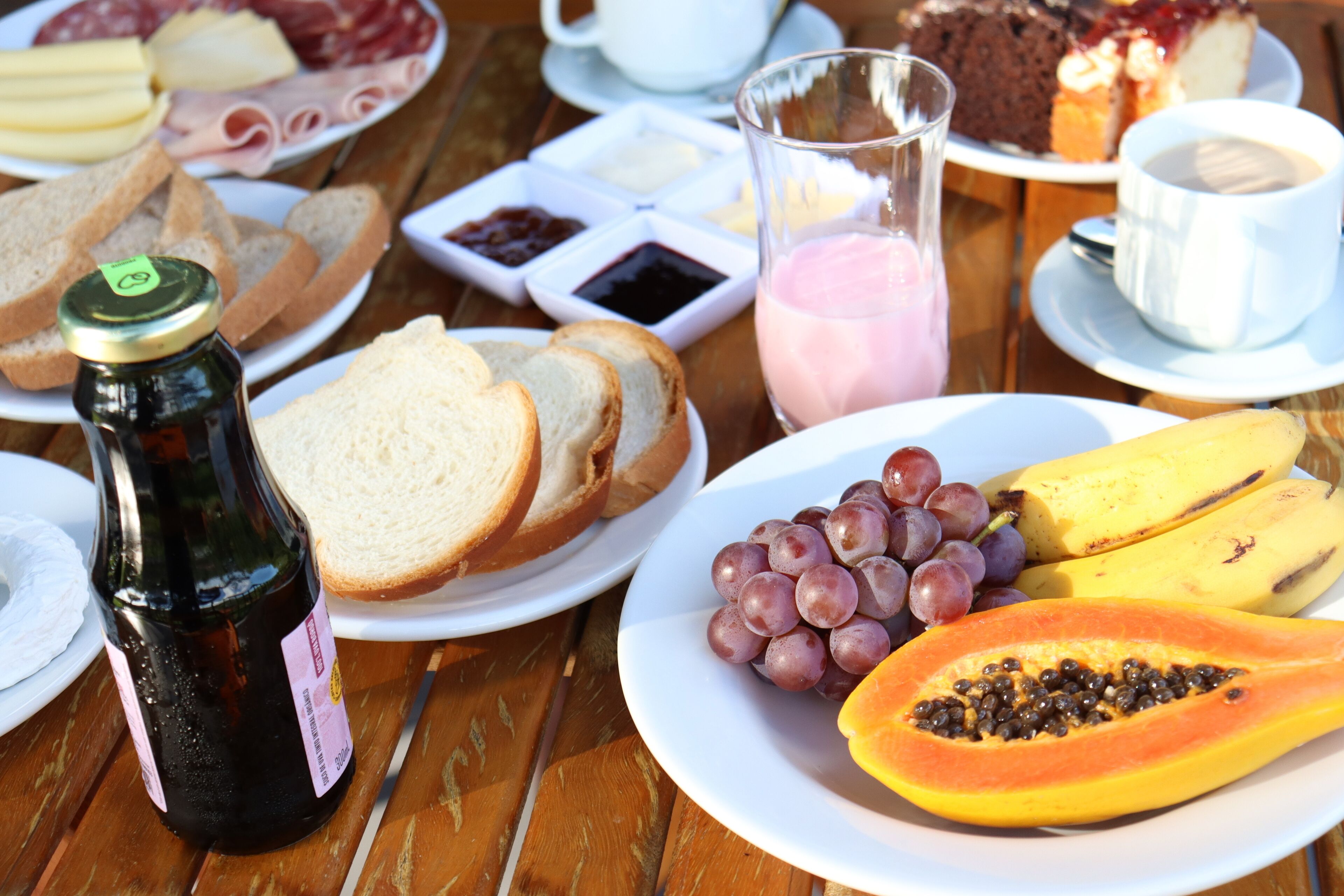 Une table sur laquelle on trouve divers aliments, notamment du pain, des raisins, des bananes et une papaye.