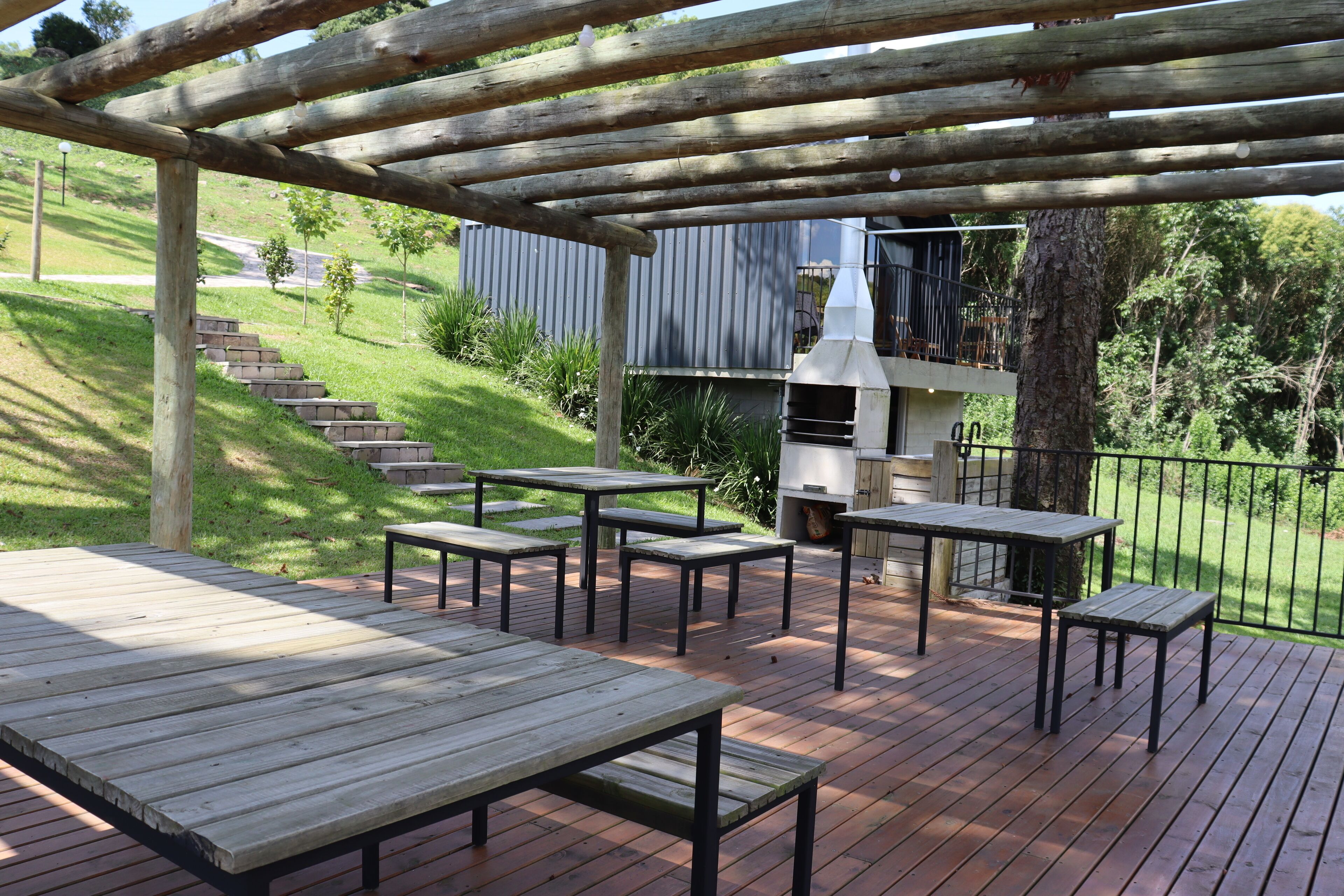 Une terrasse en bois avec des tables de pique-nique et un barbecue.
