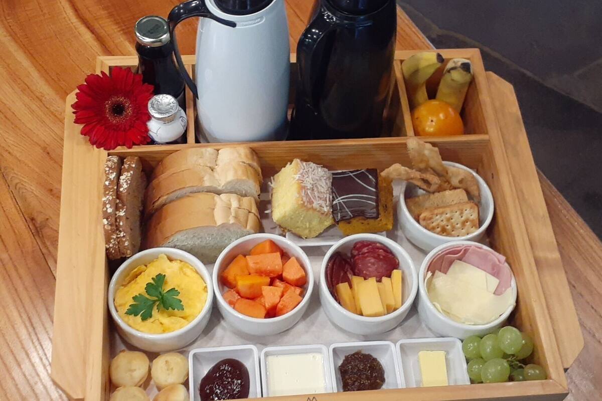 A wooden box containing various food items and condiments, including bread, cheese, and fruits.