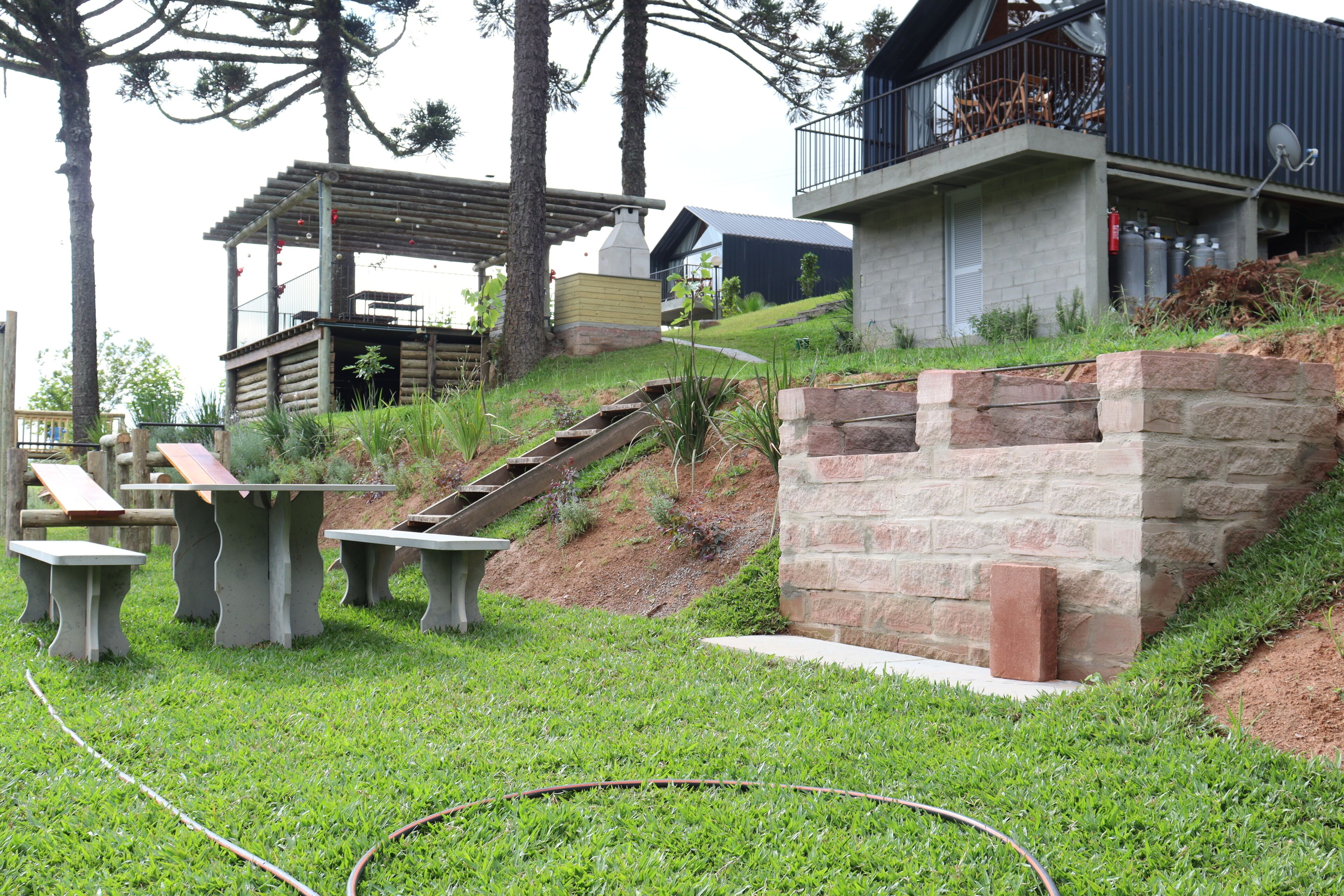 A modern outdoor area with a wooden pergola, stone benches, and a stone retaining wall.