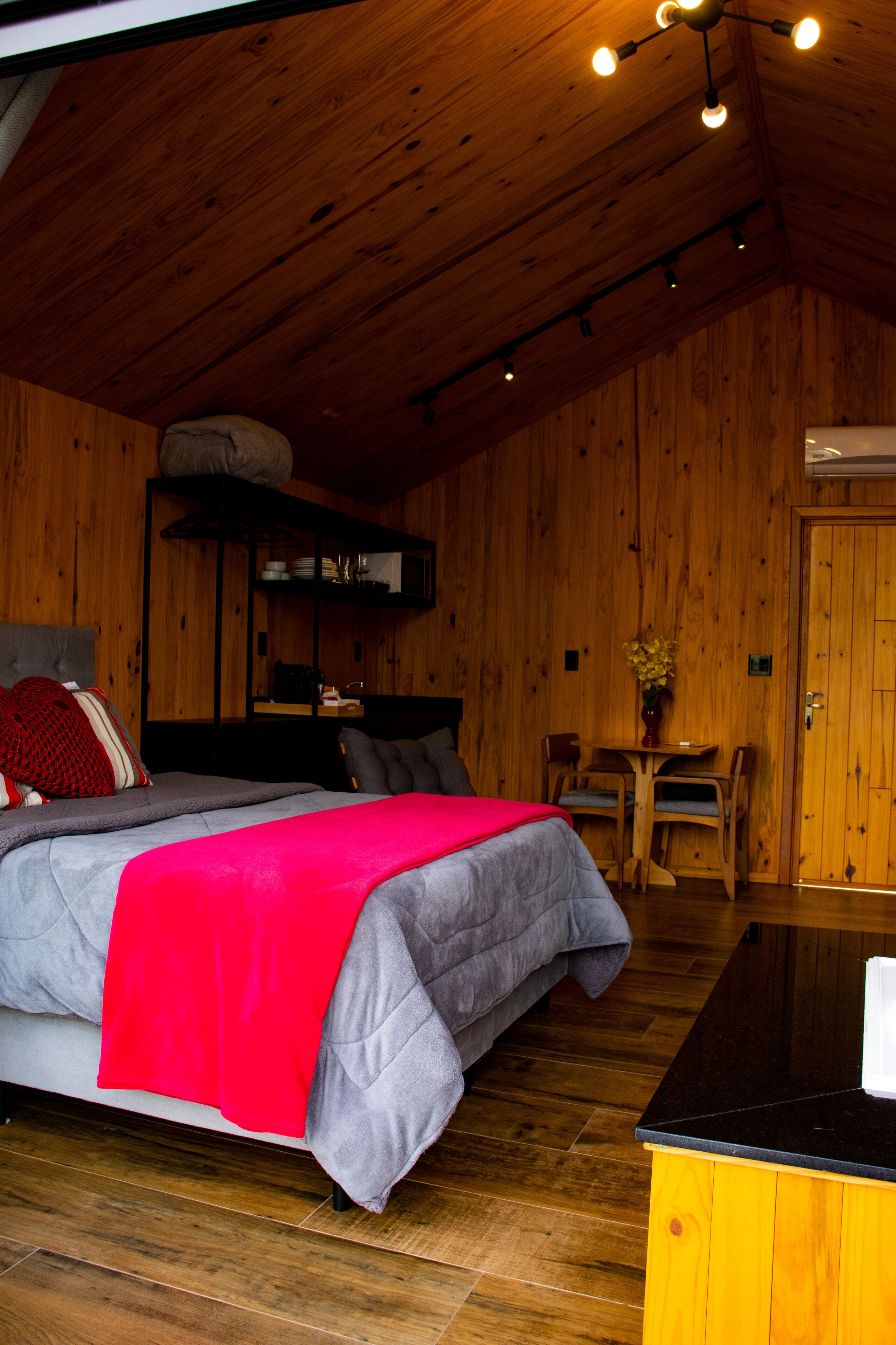 A wooden-paneled room with a bed, a small table, and a chair.