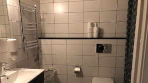 Une petite salle de bain avec un lavabo blanc, des toilettes et un espace douche.