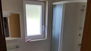 Une petite salle de bain avec des toilettes, un lavabo et une douche.