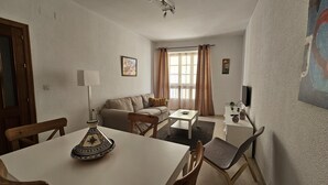 Ein Wohnzimmer mit einer Couch, einem Couchtisch, einem Fernseher und einem Essbereich mit Stühlen und einem Tisch.