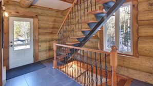 A wooden interior with a spiral staircase, a door, and windows. - Chalet en Bois Rond Avec Spa, Sauna et Hammam (Labelle)