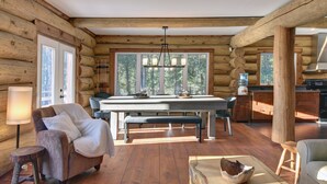 A log cabin interior with a dining area, wooden furniture, and large windows. - Chalet en Bois Rond Avec Spa, Sauna et Hammam (Labelle)