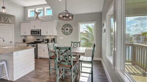 A spacious kitchen with white cabinets, a central island, and a dining area with mismatched chairs. - Paradise Vibes- Pond Views | 2 Balconies (Port Aransas)