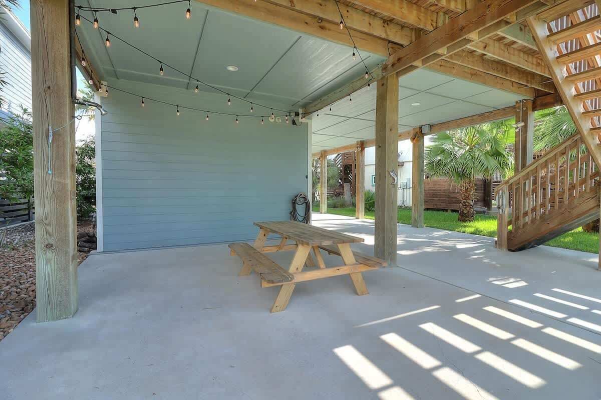 A covered patio with a wooden table and string lights.