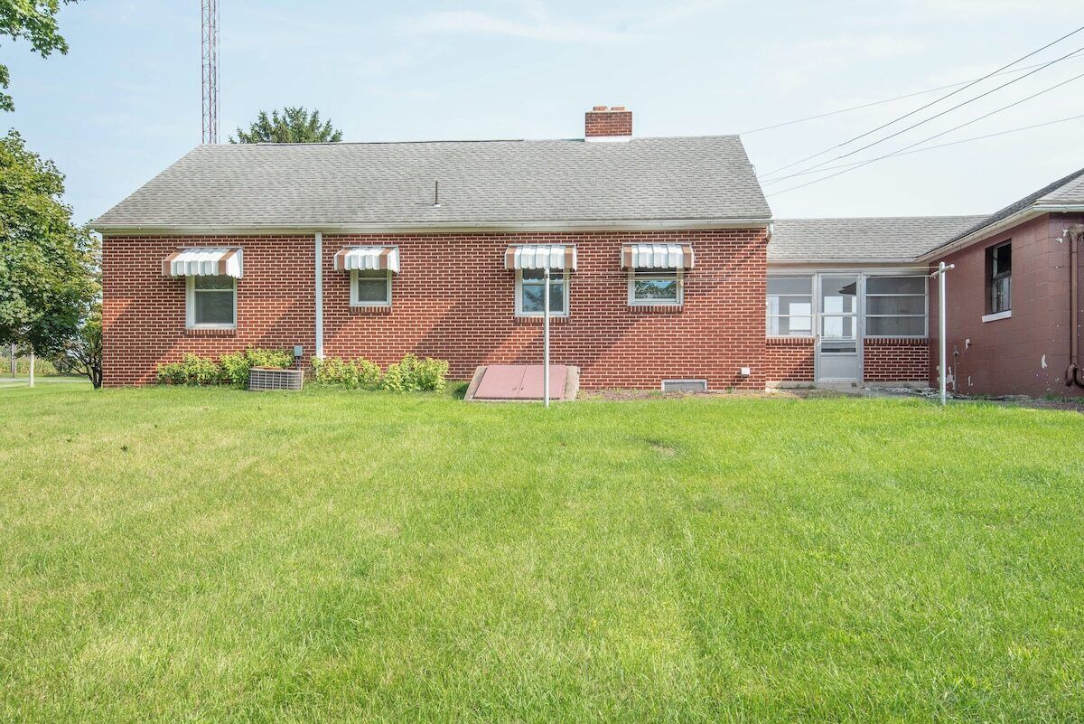 A brick building with a flat roof, a small front porch, and a grassy yard.