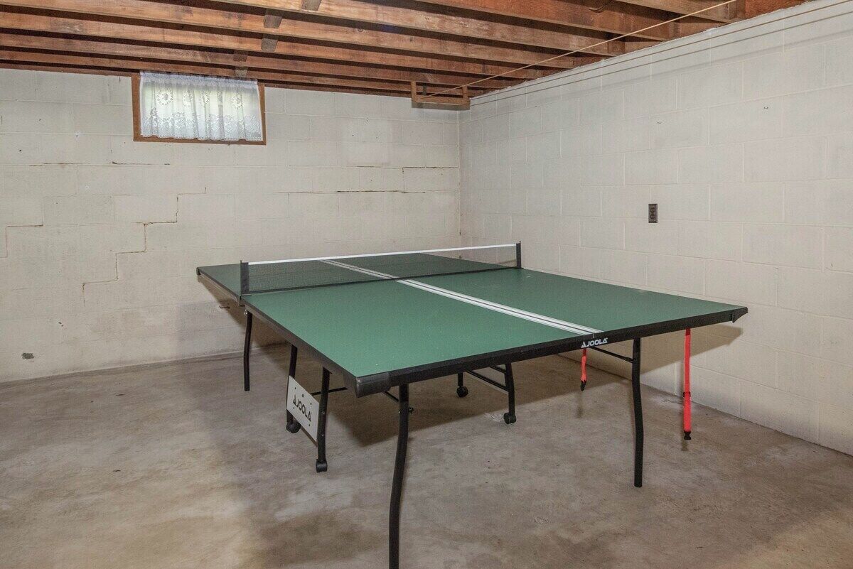 A ping pong table in a room with white brick walls and a wooden ceiling.