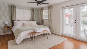 A bedroom with a bed, a ceiling fan, a bench, a nightstand, and a window with blinds. - Relaxed 3BR retreat w/ heated pool & patio (Clearwater)