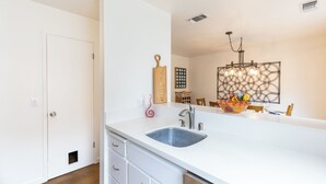 A modern kitchen with a large island, white cabinetry, and a hanging light fixture.