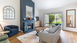 A modern living room with a fireplace, a sofa, a coffee table, and a view of the outdoors.