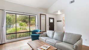 A living room with a sofa, a coffee table, and a view through large glass doors.
