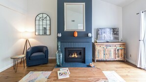 A living room with a fireplace, a television, and a blue armchair.