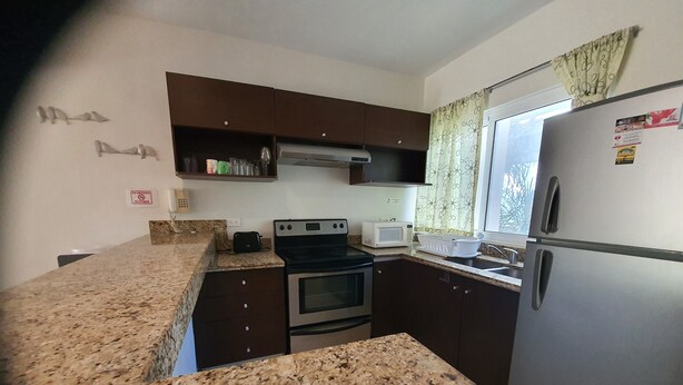 A kitchen with granite countertops, a stove, a microwave, and a refrigerator. - Luxury and Boutique Apartment by Bookhap (Playa del Carmen)