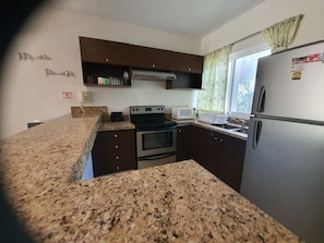 A kitchen with granite countertops, a stove, a microwave, and a refrigerator. - Luxury and Boutique Apartment by Bookhap (Playa del Carmen)
