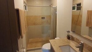 A modern bathroom with a shower, toilet, sink, and a large mirror. - Luxury and Boutique Apartment by Bookhap (Playa del Carmen)