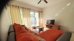 A room with a large bed, a TV on a wooden cabinet, and a balcony with curtains. - Luxury and Boutique Apartment by Bookhap (Playa del Carmen)