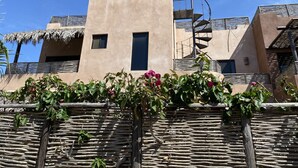 A modern building with a spiral staircase, a small window, and a thatched roof. - Authentic 3-story Mexican Villa with Rooftop Views - 5 min from the beach! (El Pescadero)