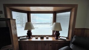 Ett rum med ett stort fönster, två lampor, en tv och en fåtölj i läder.