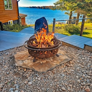 A fire pit on a deck with a lake view.