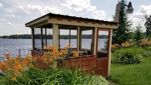 A gazebo with a view of a lake, surrounded by green plants and flowers. - Lakeview Retreat, Lakeside on the Flowage (Butternut)