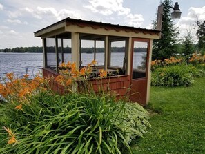 A gazebo with a view of a lake, surrounded by green plants and flowers. - Lakeview Retreat, Lakeside on the Flowage (Butternut)