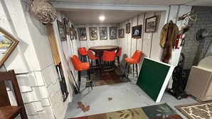 A room with a round table and orange chairs, a wall with framed pictures, and a mounted animal head. - Lakeview Retreat, Lakeside on the Flowage (Butternut)