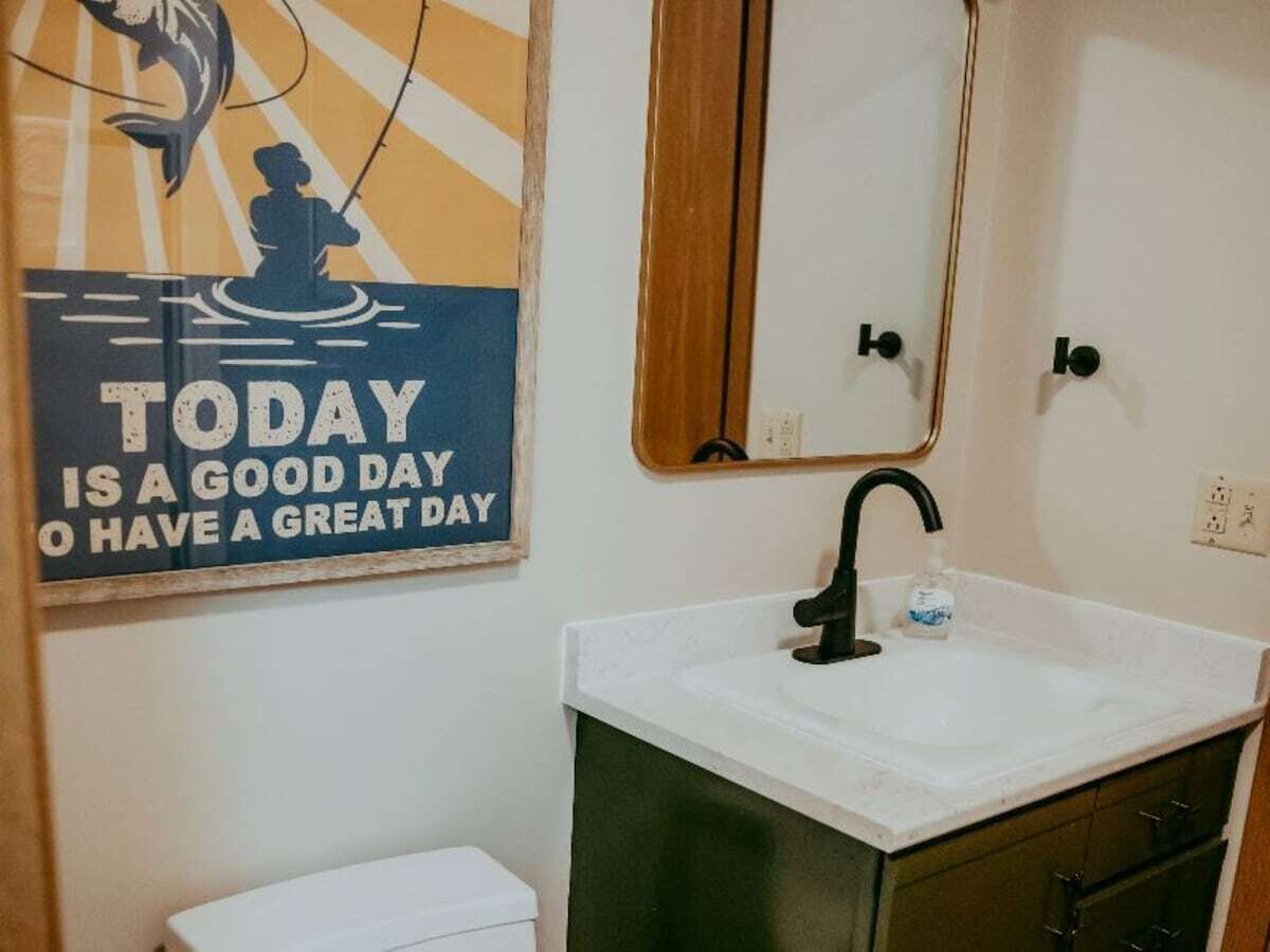 Une salle de bain avec un lavabo, un miroir et une affiche motivante accrochée au mur.