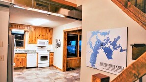 Una cocina moderna con armarios de madera, un microondas y una estufa. Hay un mapa en la pared y una escalera que sube.