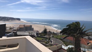 A coastal view with a beach, ocean, and residential buildings. - Mom Home-007 (caldas da Rainha)