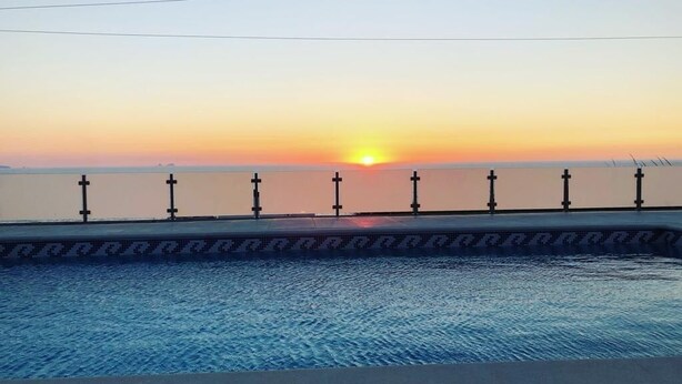 A swimming pool with a sunset view, surrounded by a low fence with evenly spaced vertical posts. - Mom Home-007 (caldas da Rainha)