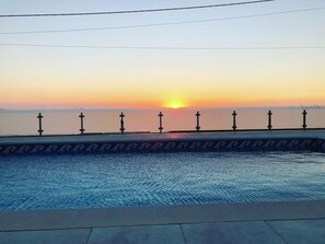 A swimming pool with a sunset view, surrounded by a low fence with evenly spaced vertical posts. - Mom Home-007 (caldas da Rainha)