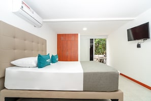 Une chambre d’hôtel moderne équipée d’un grand lit, d’une armoire en bois, d’une télévision et d’un climatiseur.