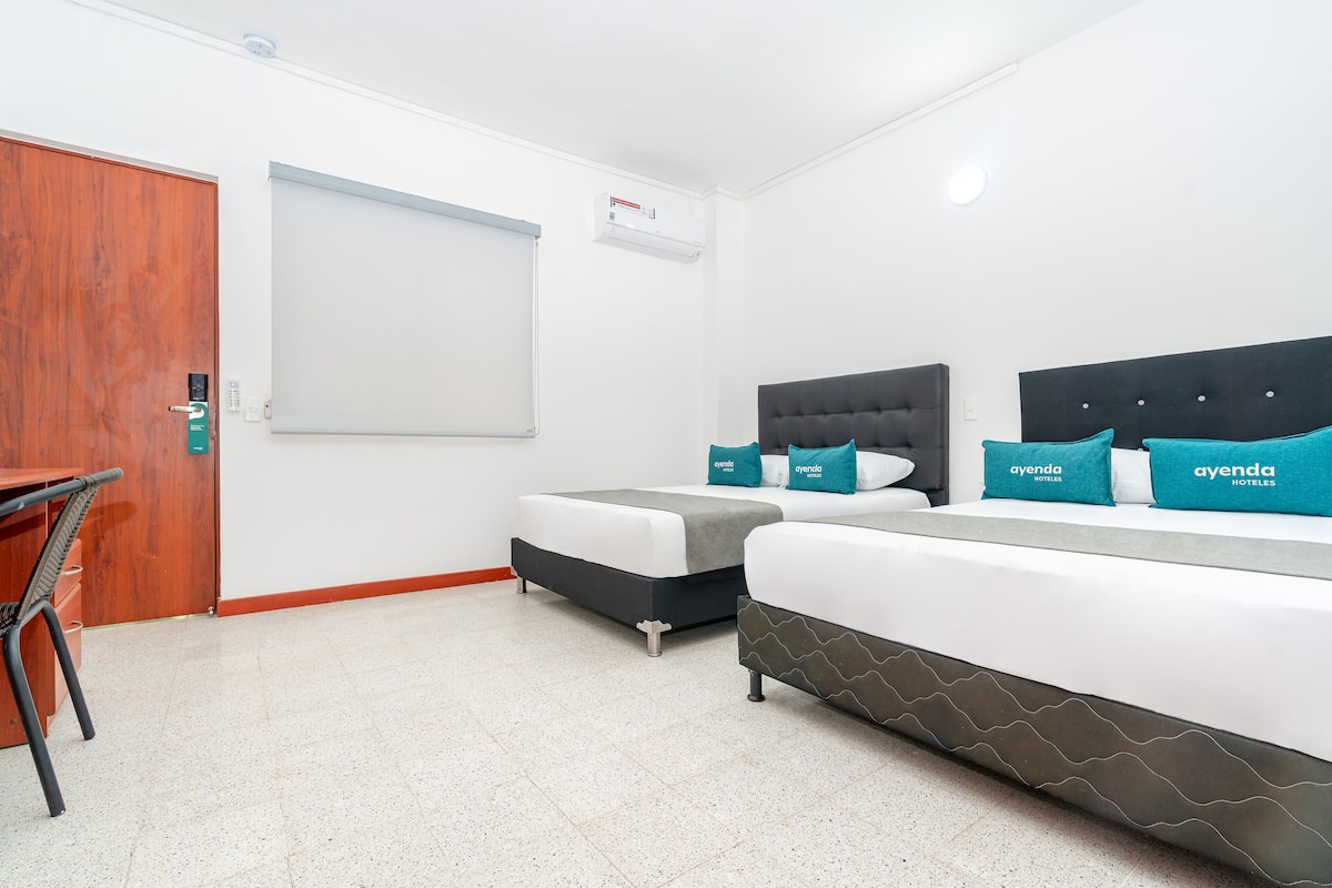 Una habitación de hotel con dos camas, un escritorio y una pizarra en la pared.