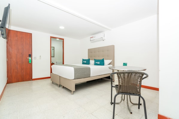 Une chambre d’hôtel équipée d’un lit, d’une chaise, d’une table, d’un téléviseur et d’un appareil de climatisation.