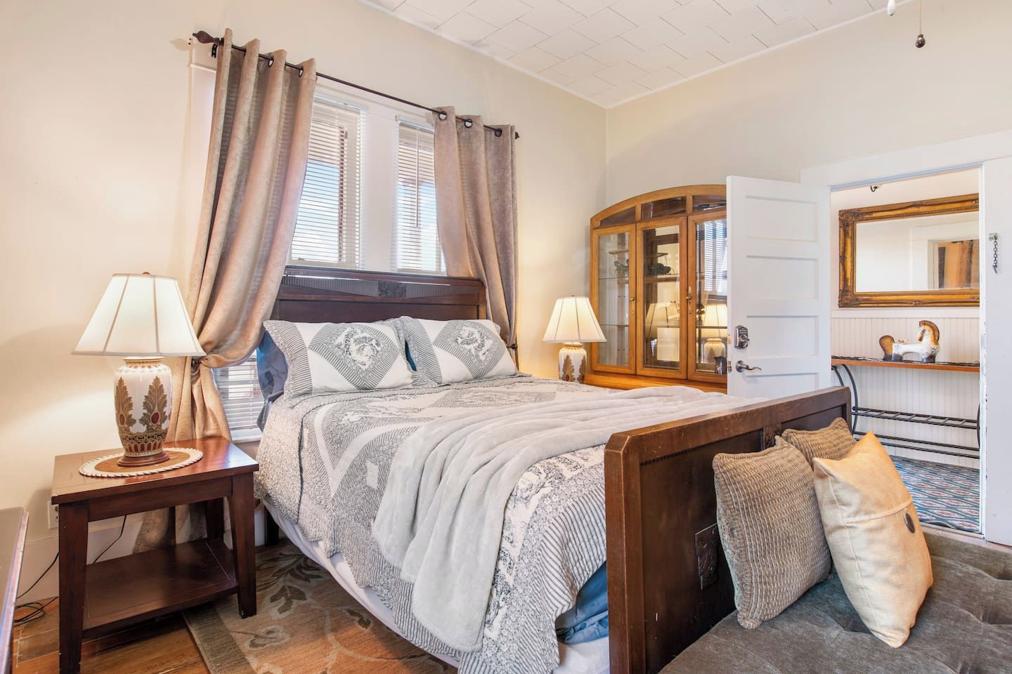 Une chambre à coucher comprenant un lit, deux tables de chevet avec des lampes, une armoire et un miroir.