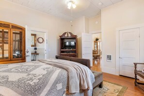 A bedroom with a large bed, a television, a wooden cabinet, and a mirror.