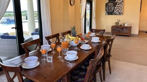 Un comedor con una mesa dispuesta para el desayuno, con frutas y zumo de naranja, cerca de una piscina.
