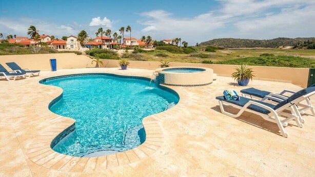 Una piscina con sillas de descanso y vistas a casas al fondo.