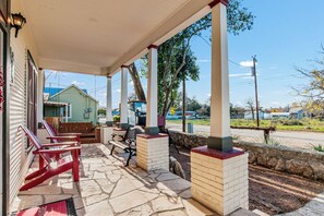 A covered outdoor seating area with stone flooring and wooden benches. - Carriage Inn - Bandera Suite 2 (Bandera)
