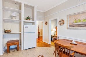 A kitchen with white cabinetry, a wooden bench, a dining table with chairs, and a refrigerator. - Carriage Inn - Bandera Suite 2 (Bandera)