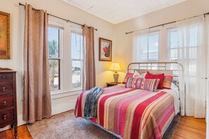 A bedroom with a bed, a dresser, a lamp, and a painting on the wall. - Carriage Inn - Bandera Suite 2 (Bandera)