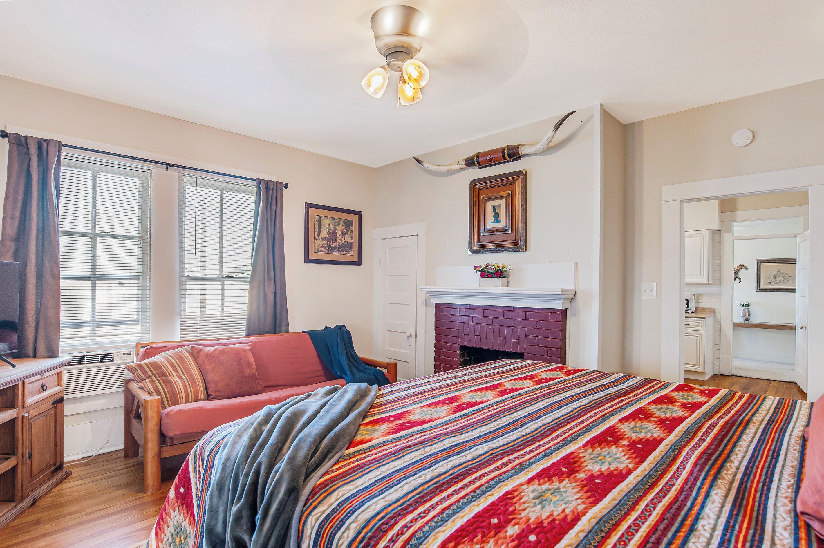 Quarto com cama, sofá, lareira e ventoinha de teto.