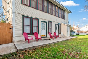 A two-story house with a covered porch, a wooden fence, and a lawn with scattered leaves.