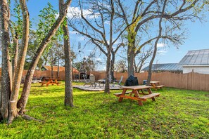 A backyard with picnic tables, a barbecue area, and a stone fireplace. - Carriage Inn - Hondo Suite 3 (Bandera)