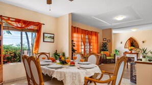 A dining area with a round table set for four, surrounded by wicker chairs.